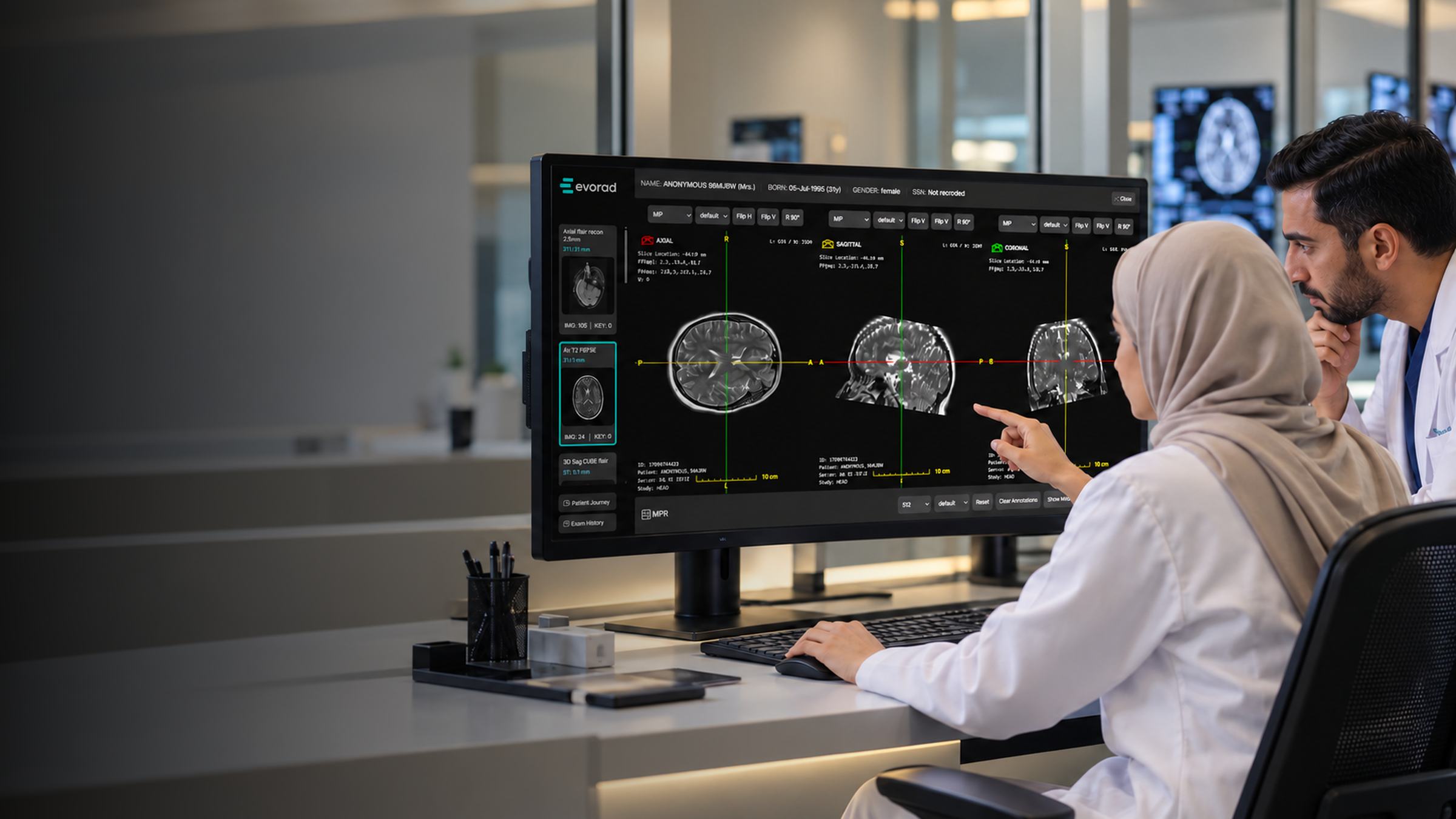 A clinician in a hijab and a colleague reviewing brain scans on an Evorad viewer